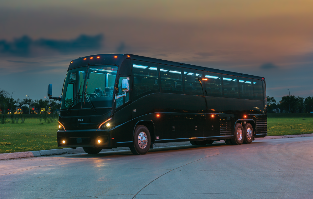 MCI J4500 bus on road with backlit sunset