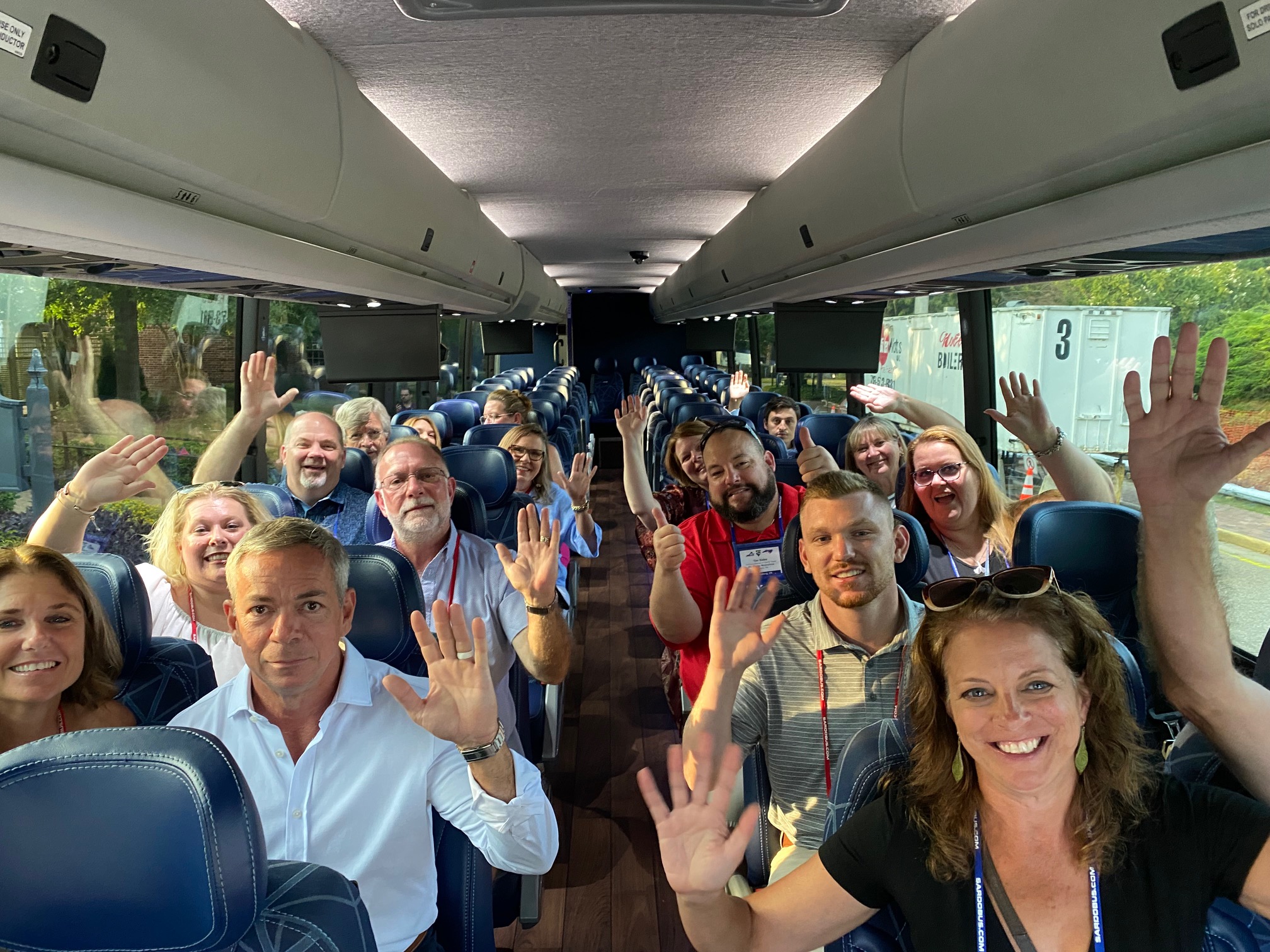 An image provided by Amaya-Astron Seating, showing a large group of people sitting in a bus and waving.